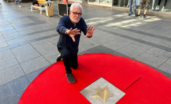 A person kneeling on a red carpet Description automatically generated